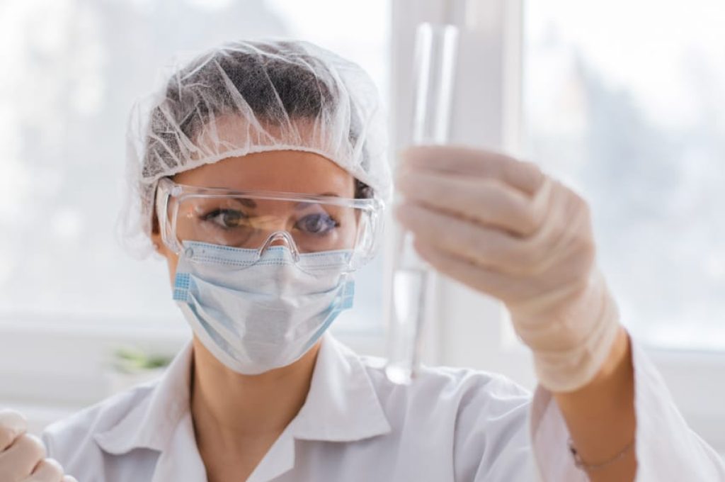 women inspecting test tub in lab clean room environment